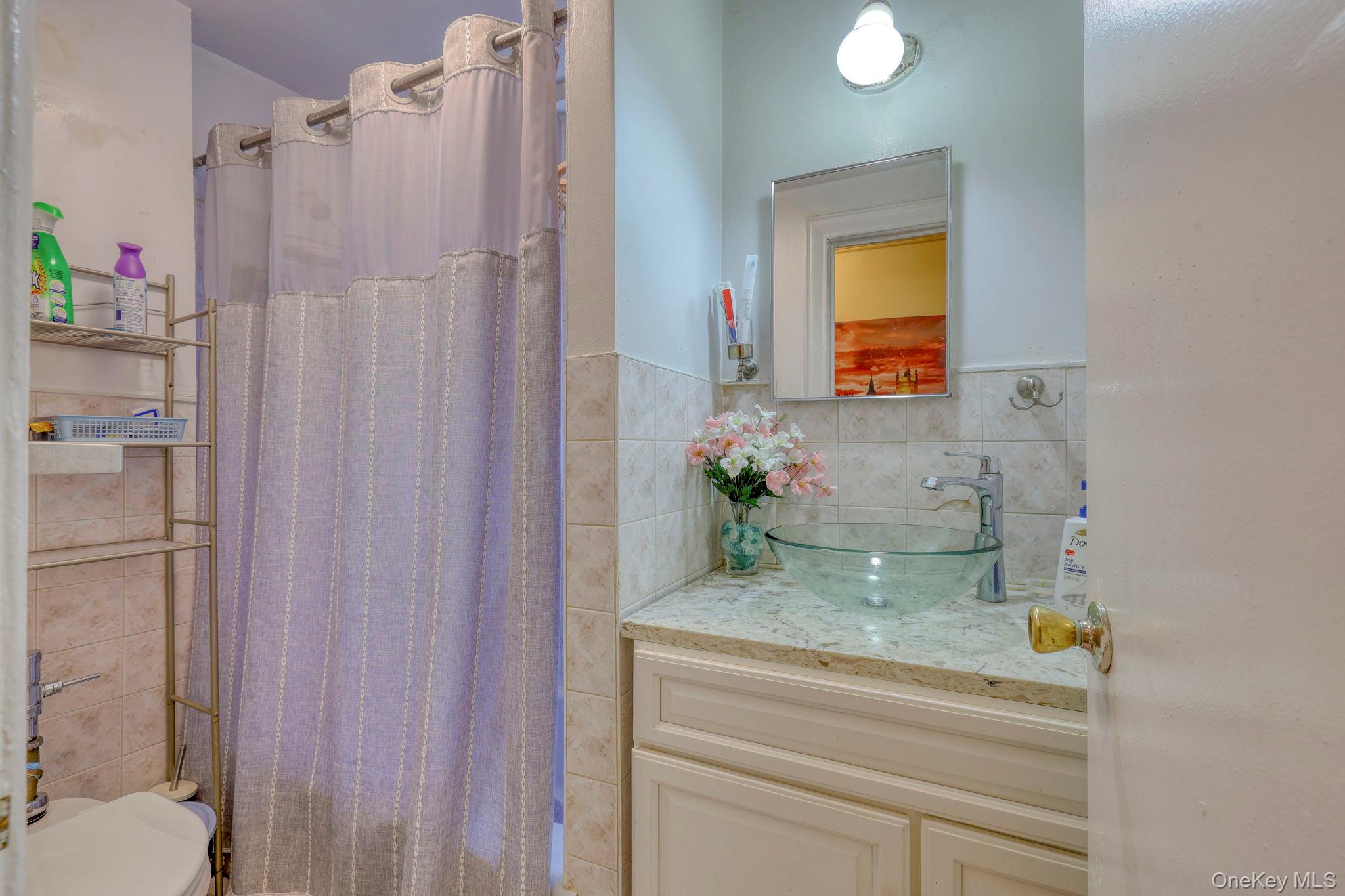 1372 Shakespeare Avenue, Unit 2H Bronx, NY 10452 - Photo 12 of 14 a bathroom with a granite countertop sink and a mirror