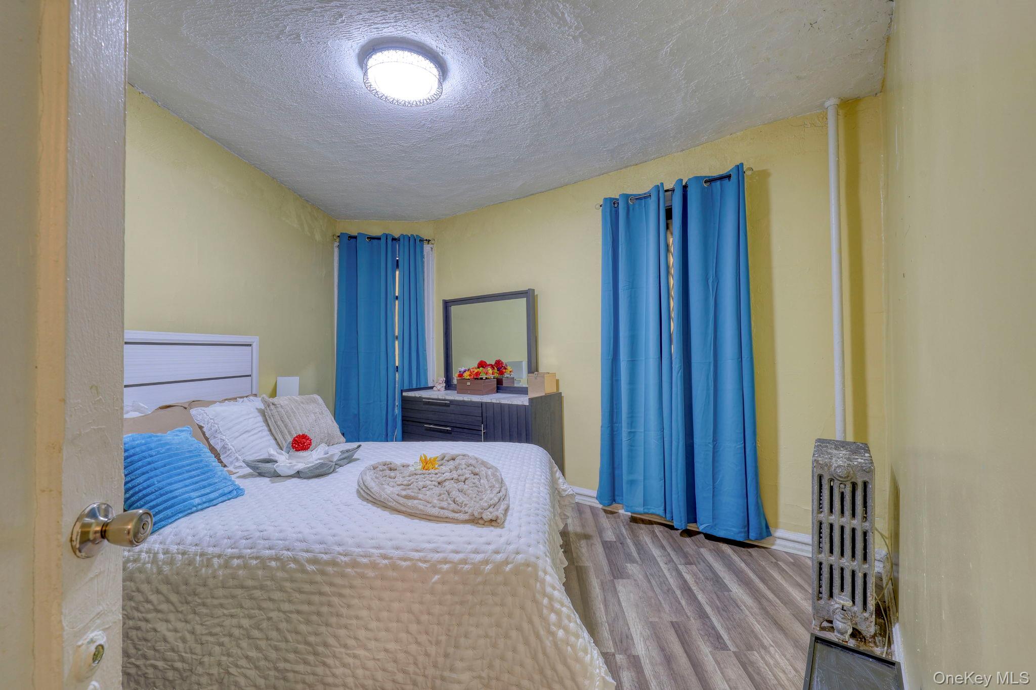 1372 Shakespeare Avenue, Unit 2H Bronx, NY 10452 - Photo 10 of 14 a bedroom with a bed and wooden floor