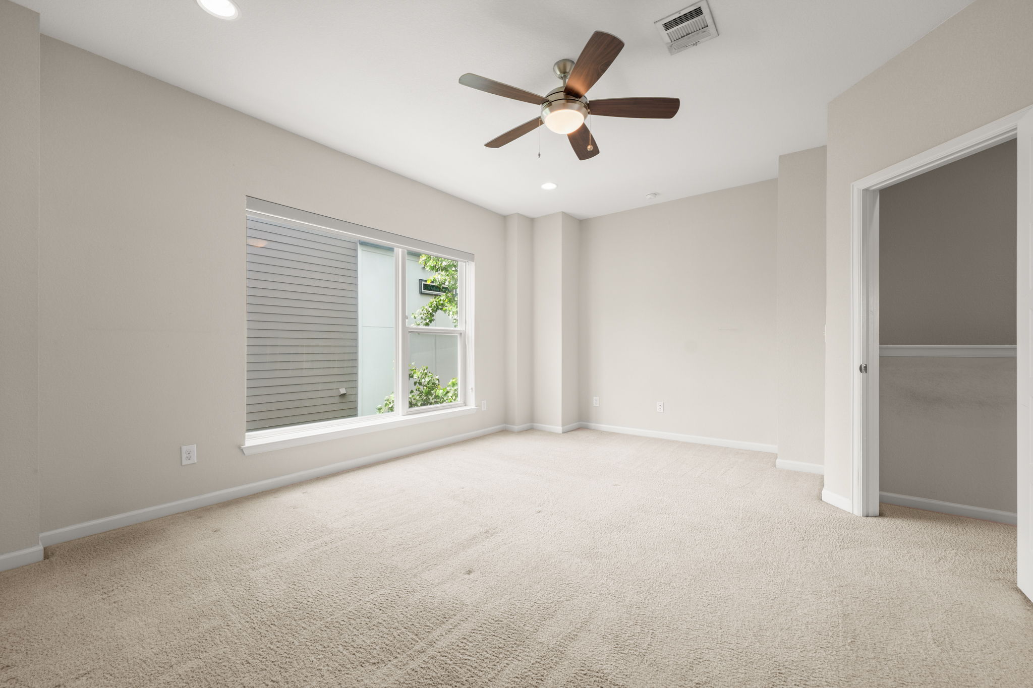 4403 Swift Path Austin, TX 78741 - Photo 13 of 32 Spacious room featuring neutral carpet flooring, a large window, recessed lighting, and a ceiling fan