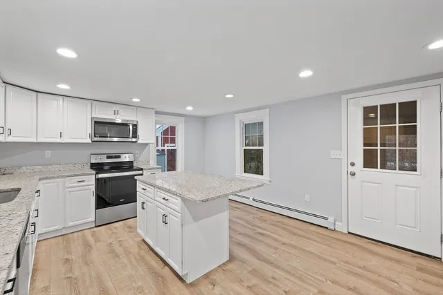 a kitchen with granite countertop white cabinets and white appliances