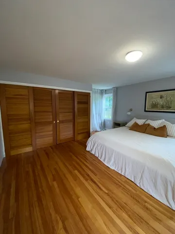a spacious bedroom with a bed and wooden floor