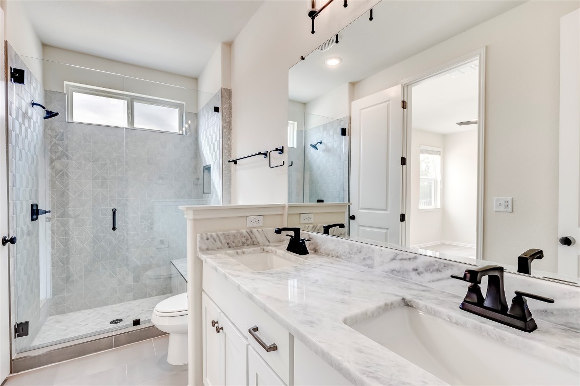 2008 Kit Circle Austin, TX 78758 - Photo 23 of 37 Full bath with double vanity, a stall shower, and light tile patterned flooring
