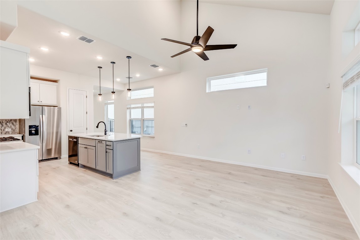 2008 Kit Circle Austin, TX 78758 - Photo 9 of 37 Kitchen featuring pendant lighting, stainless steel refrigerator with ice dispenser, gray cabinetry, light wood-type flooring, and ceiling fan