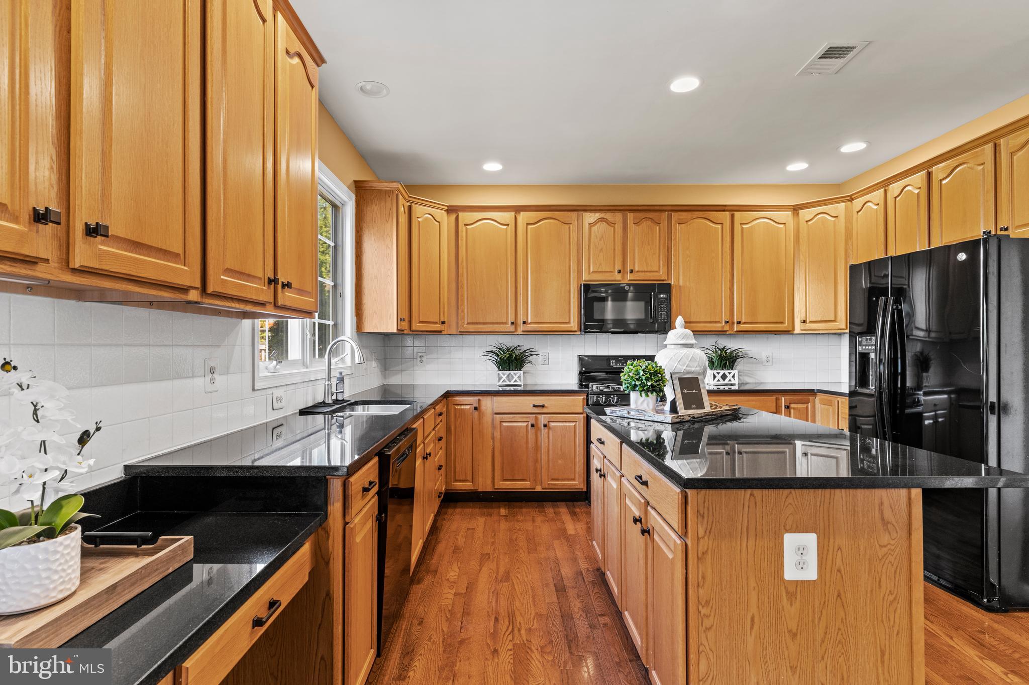 42714 Freedom Street Chantilly, VA 20152 - Photo 11 of 47 a kitchen with granite countertop a refrigerator a sink dishwasher stove top oven and wooden cabinets