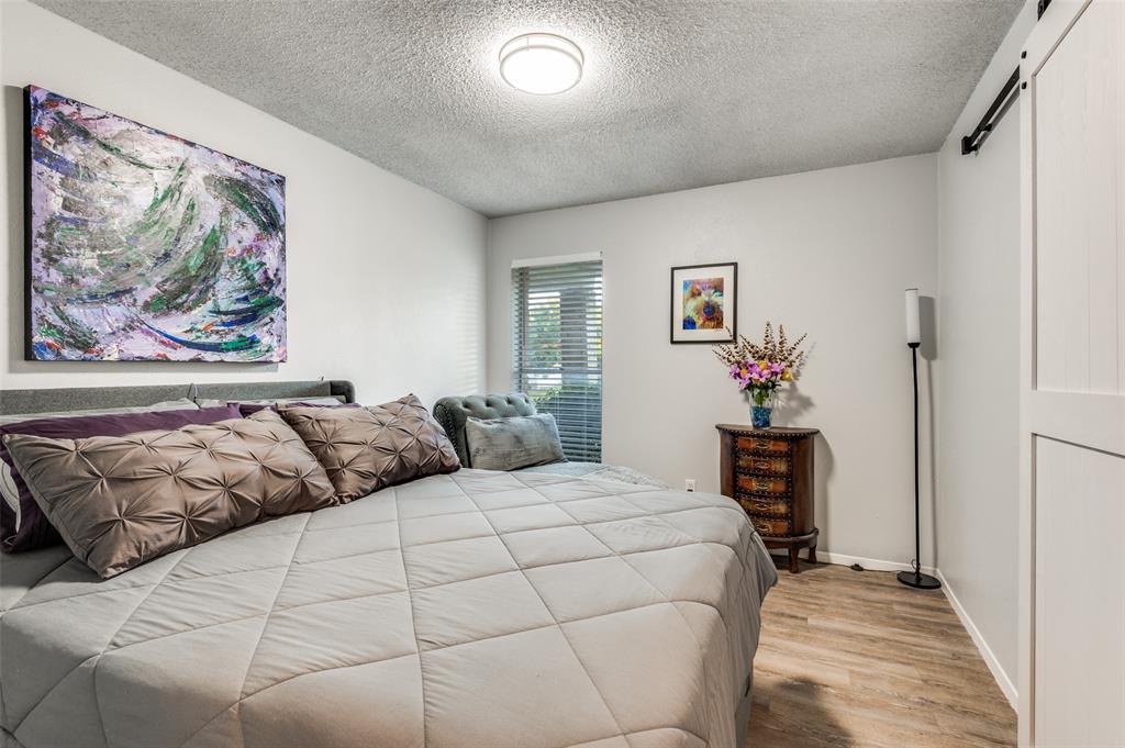 37 Merrie Circle Richardson, TX 75081 - Photo 18 of 28 Bedroom featuring a barn door, wood finished floors, and a textured ceiling