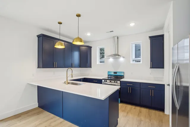 a kitchen with stainless steel appliances granite countertop a sink a stove and a refrigerator