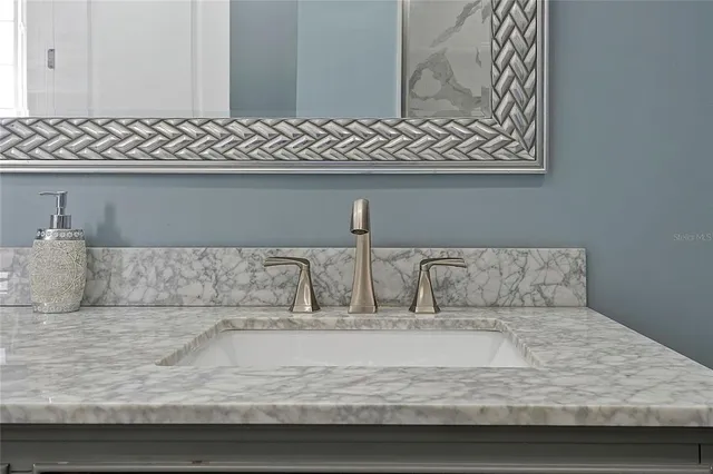 a bathroom with a granite countertop sink and a mirror
