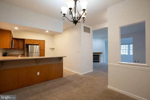 a view of a living room a chandelier and kitchen view