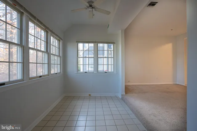 an empty room with windows and chandelier fan