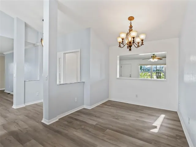 a view of a hallway with wooden floor and a chandelier