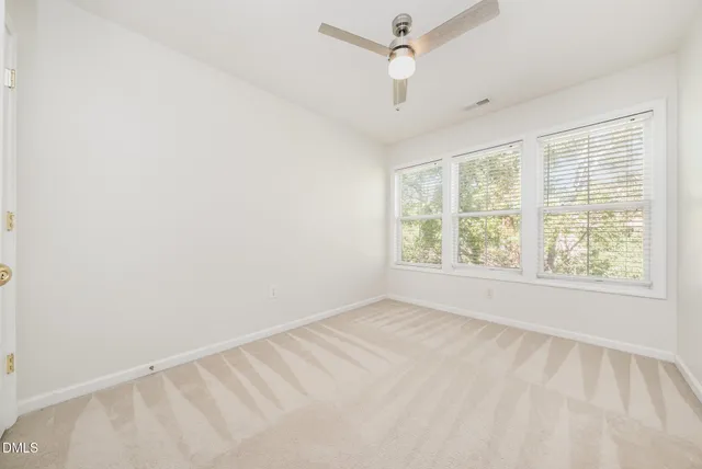 an empty room with a window and ceiling fan