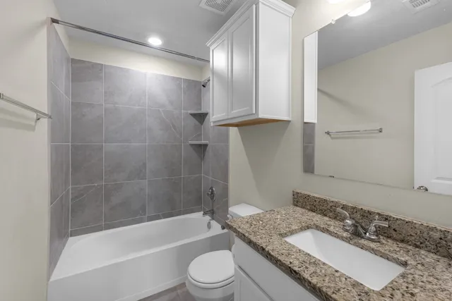 a bathroom with a granite countertop tub sink toilet and mirror