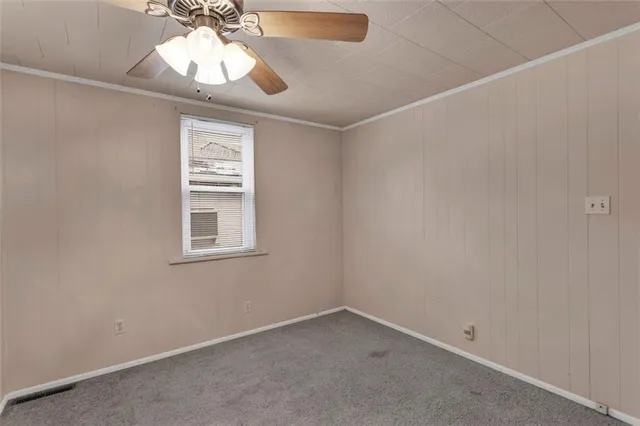 an empty room with a chandelier fan and windows