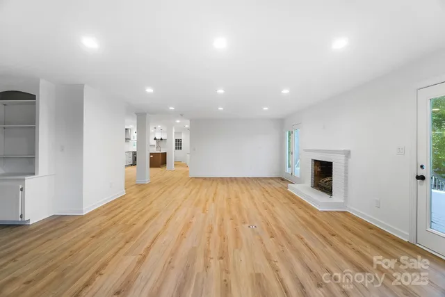 a view of empty room with wooden floor and fireplace