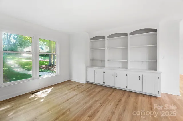 a view of an empty room with a window and wooden floor