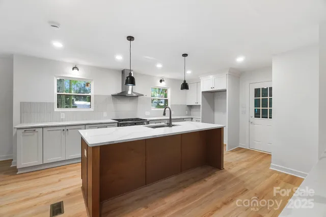 a large kitchen with stainless steel appliances granite countertop a sink a stove a refrigerator and a microwave