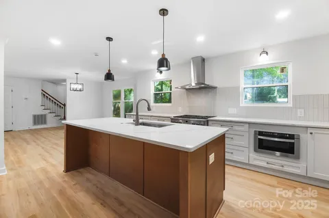 a kitchen with stainless steel appliances granite countertop a sink a stove and a wooden floors