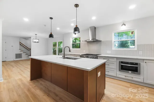 a kitchen with stainless steel appliances granite countertop a sink a stove and a wooden floors