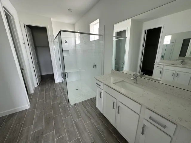 a spacious bathroom with a double vanity sink a large mirror a shower and a bathtub