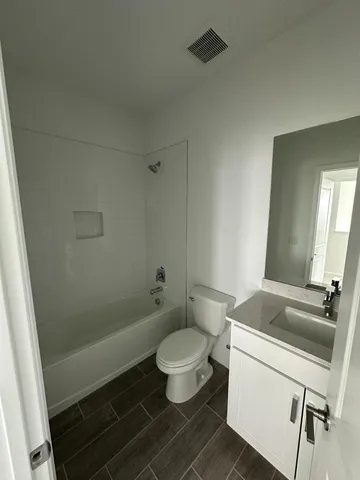 a bathroom with a granite countertop toilet a sink and a mirror