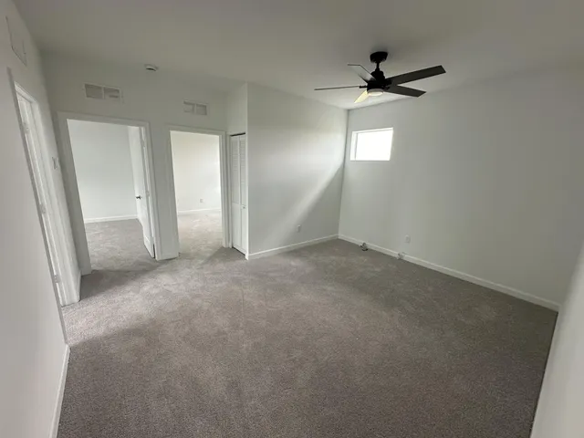 en empty room with windows and ceiling fan