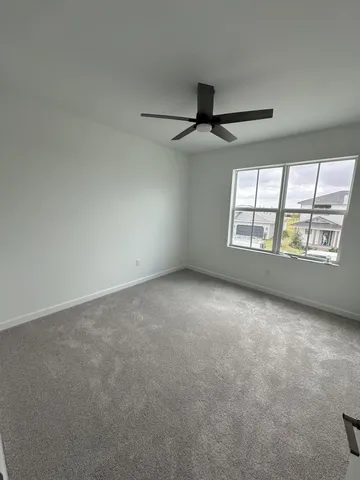 an empty room with windows and ceiling fan