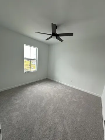 an empty room with windows and chandelier fan