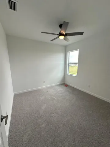 an empty room with a window and ceiling fan