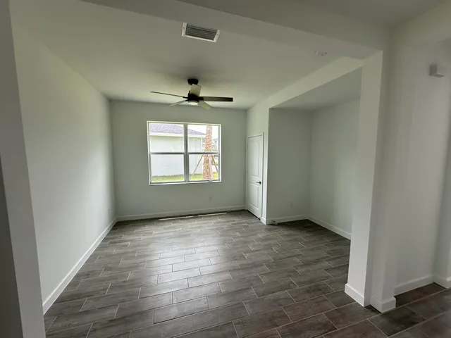 an empty room with wooden floor chandelier and windows