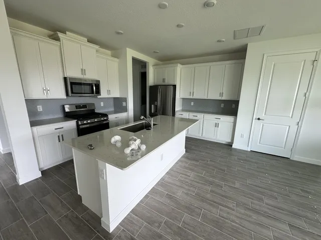 a large kitchen with stainless steel appliances granite countertop a stove a sink and a refrigerator