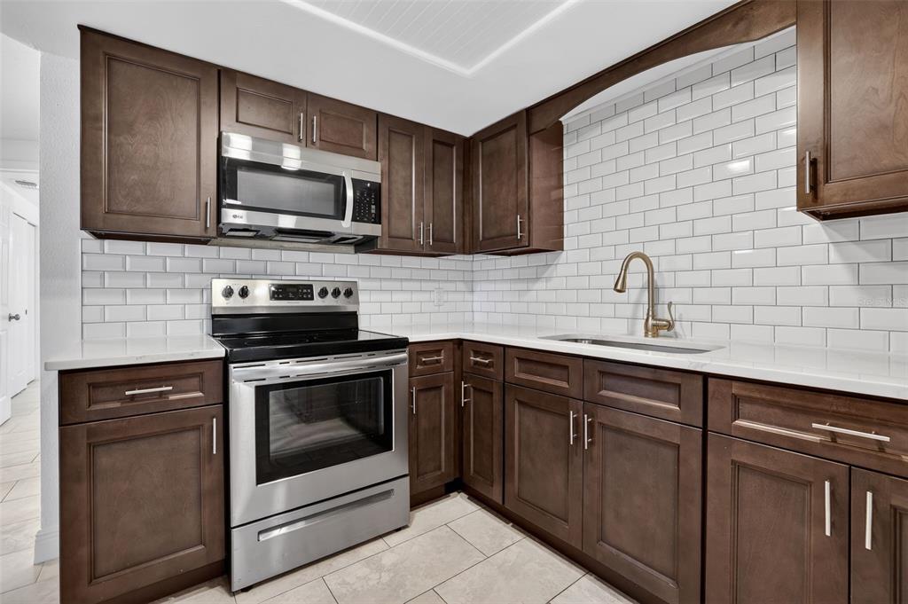 10914 Leeds Road Port Richey, FL 34668 - Photo 4 of 24 a kitchen with stainless steel appliances granite countertop a sink stove and microwave