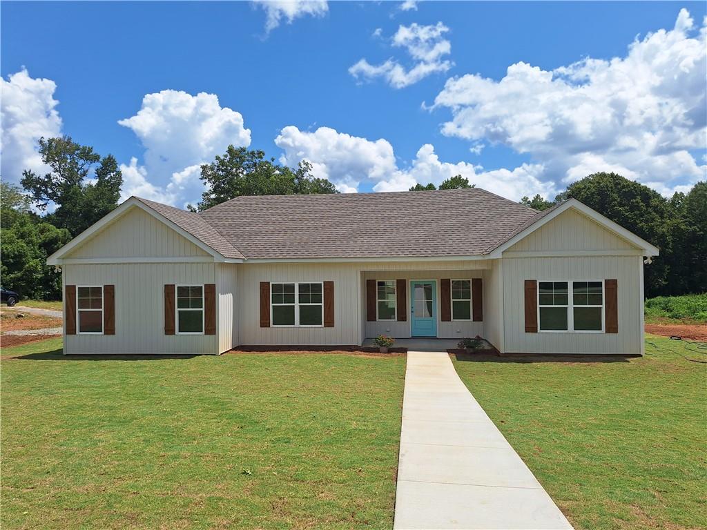 White siding with brown shutters, a light blue entry door, and a brown shingle roof