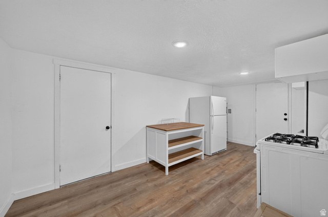 220 East Greenwood Avenue Midvale, UT 84047 - Photo 23 of 46 Contemporary kitchen featuring wood-finish flooring, white walls, recessed lighting, and a white gas range with a matching hood