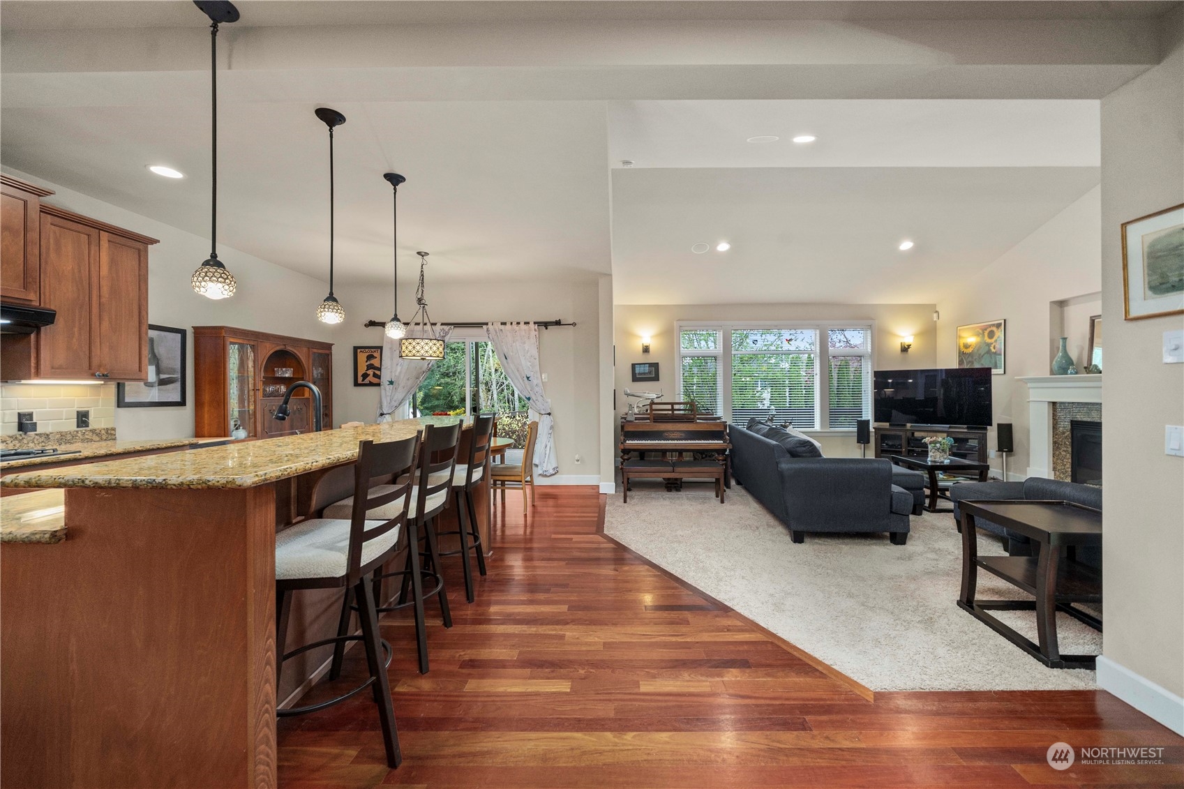 6765 Southeast 2nd Street Renton, WA 98059 - Photo 12 of 36 a open kitchen with stainless steel appliances granite countertop a stove a refrigerator a kitchen island a dining table and chairs with wooden floor