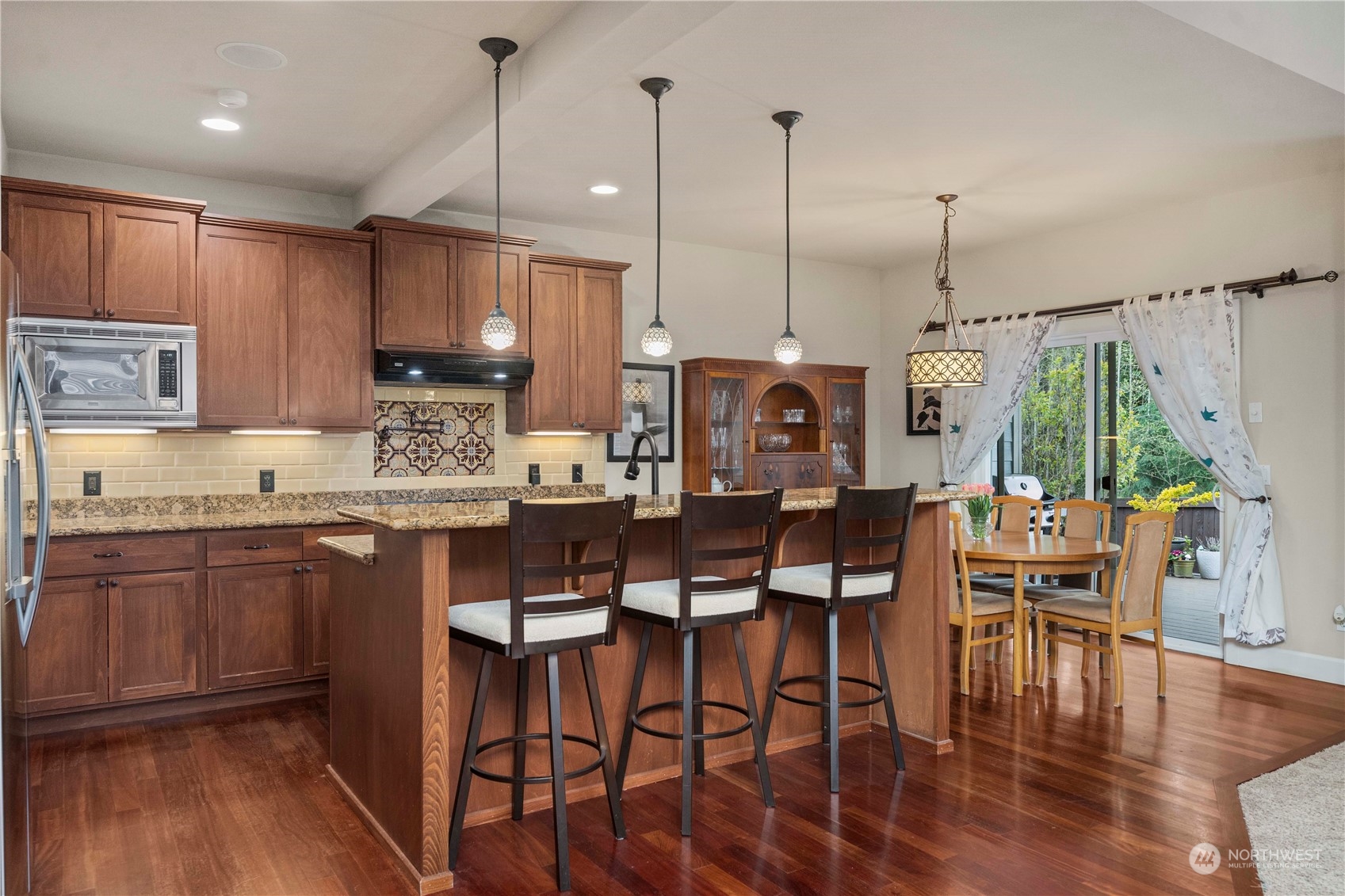 6765 Southeast 2nd Street Renton, WA 98059 - Photo 13 of 36 a kitchen with kitchen island granite countertop a table chairs sink and cabinets