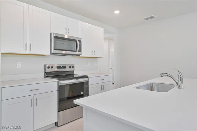 a kitchen with white cabinets appliances and a sink