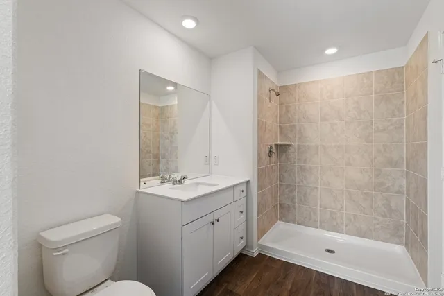 a bathroom with a granite countertop sink a toilet and shower