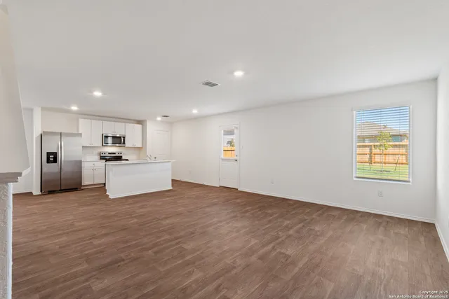 a view of a kitchen with kitchen island a sink wooden floor and white appliances