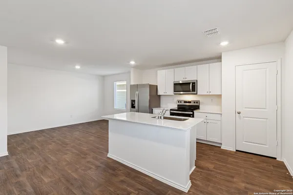 a kitchen with granite countertop a stove top oven a sink dishwasher and a refrigerator