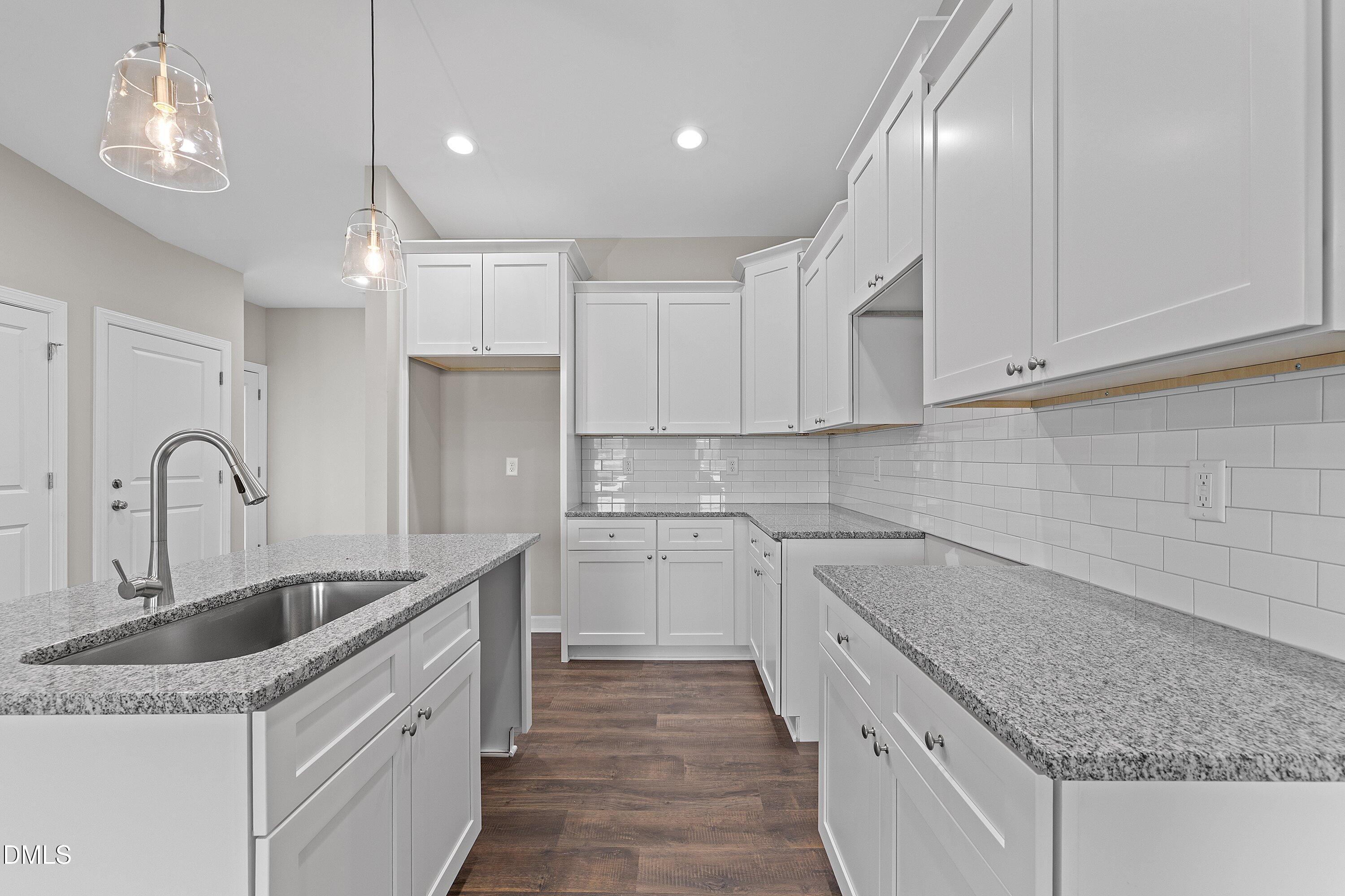 1117 Nor-Am Road Pikeville, NC 27863 - Photo 15 of 34 a kitchen with a sink dishwasher a stove and white cabinets with wooden floor