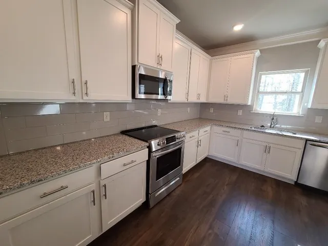 a kitchen with granite countertop white cabinets and white appliances