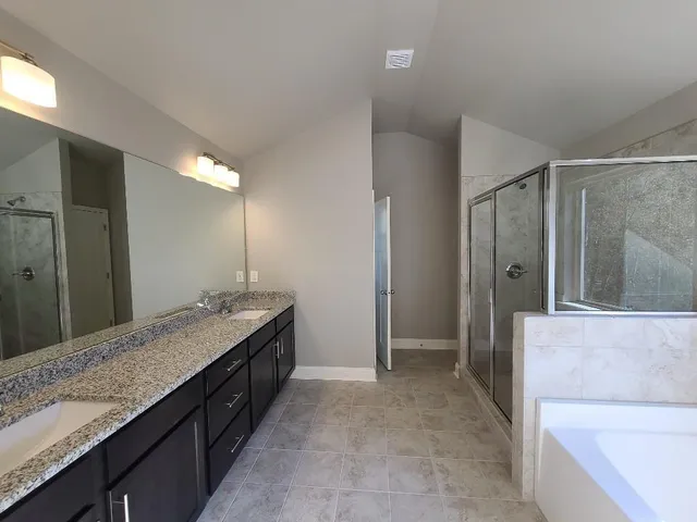 a bathroom with a granite countertop double vanity sink and mirror