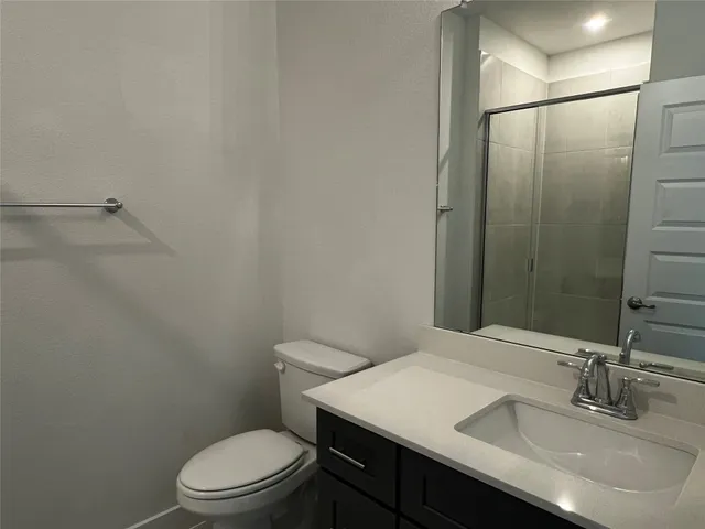 a bathroom with a granite countertop sink toilet and a mirror