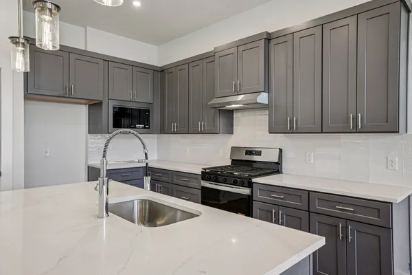 a kitchen with granite countertop a sink a stove and cabinets