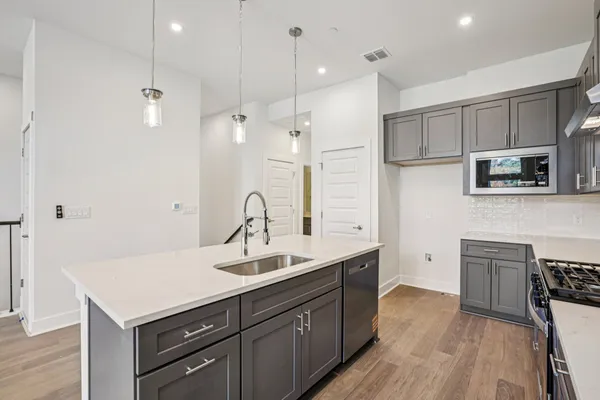 a kitchen with a sink appliances and wooden floor