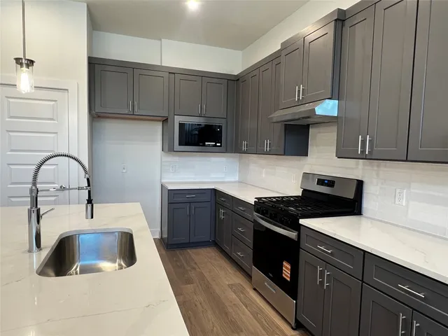 a kitchen with granite countertop a sink a stove and cabinets