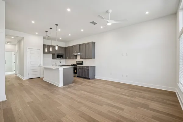 a large kitchen with stainless steel appliances a large counter top and a wooden floors
