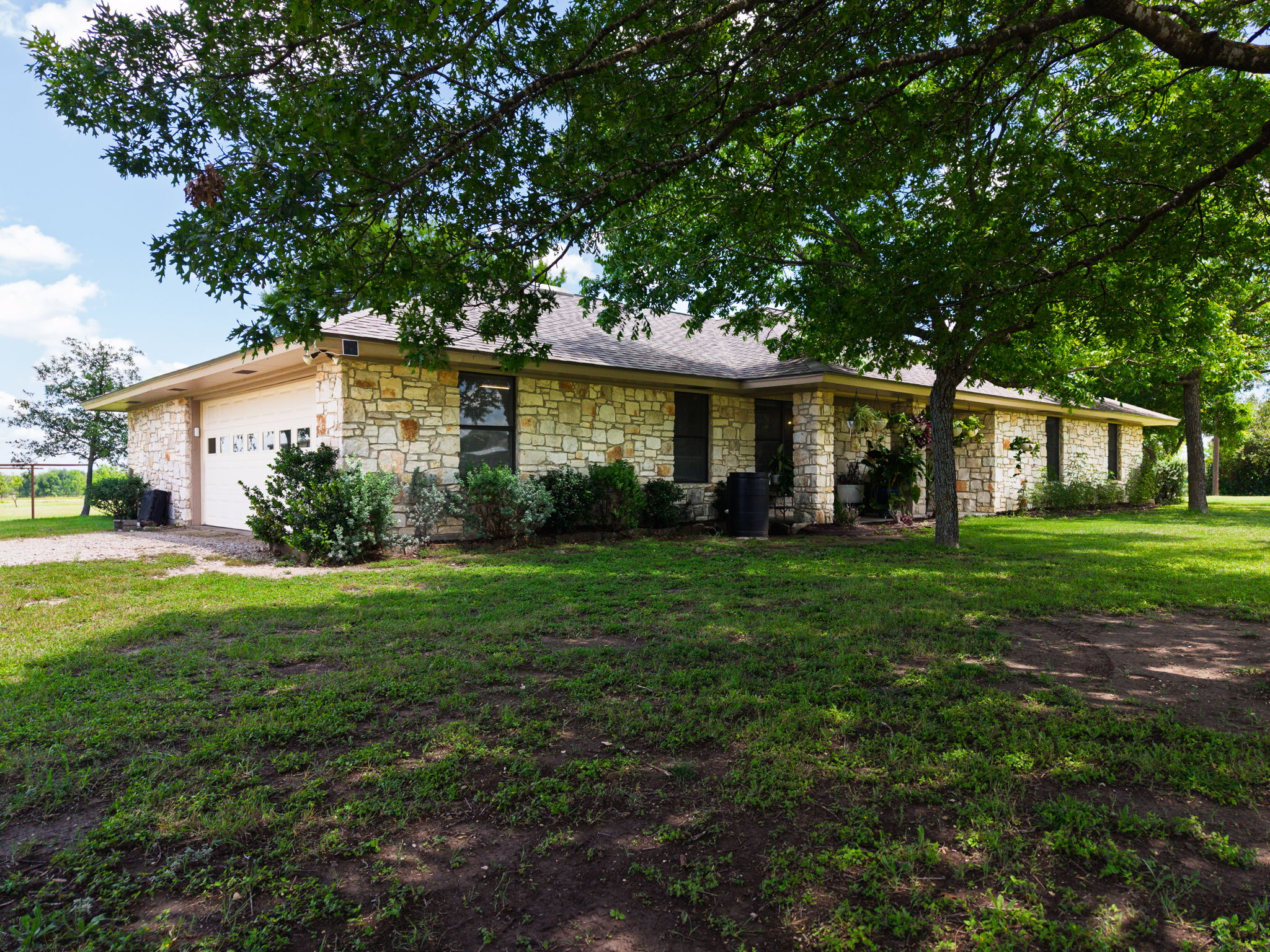 120 Rae Lane Jarrell, TX 76537 - Photo 4 of 40 Stone veneer exterior with a covered porch, attached garage, and mature shade trees