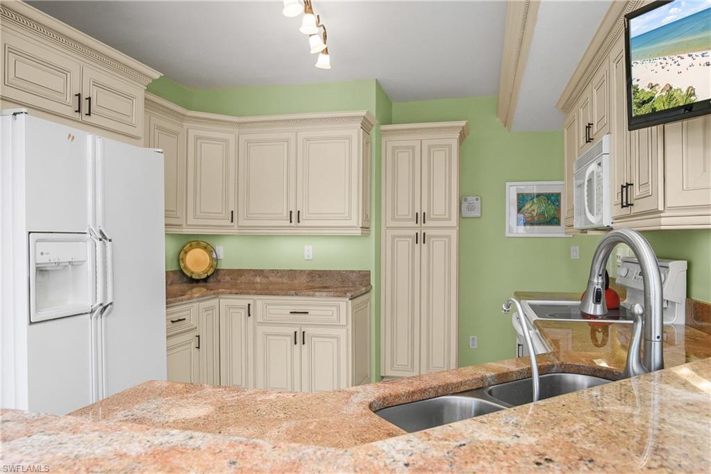 6838 Lantana Bridge Road, Unit 103 Naples, FL 34109 - Photo 30 of 41 a kitchen with stainless steel appliances kitchen island granite countertop a refrigerator and a sink