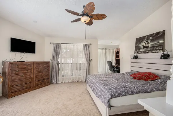 a bedroom with a bed a dresser and a flat screen television
